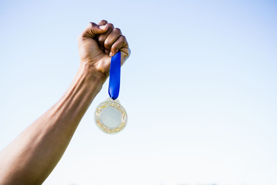Close-up of Athlete Holding Gold Medal Against Sky - Free Images, Stock Photos and Pictures on Pikwizard.com