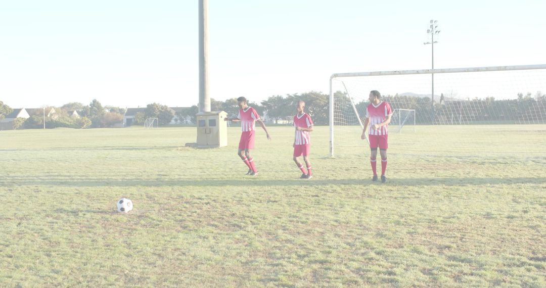 Three Soccer Players Forming Defensive Wall for Free Kick on Sunlit Grass Field