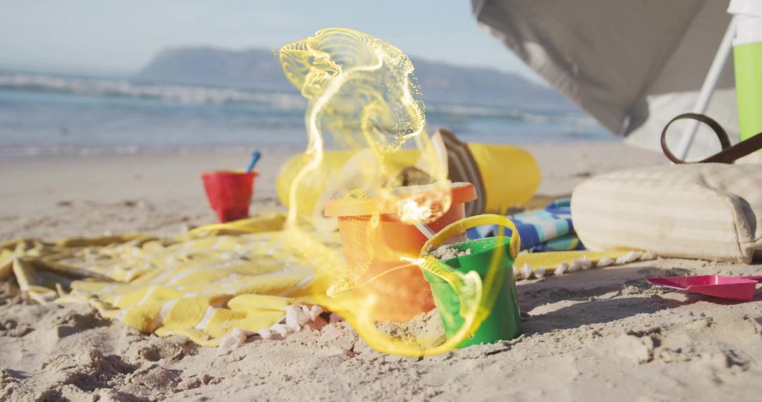 Colorful Sand Buckets on Beach with Sunny Waves in Background