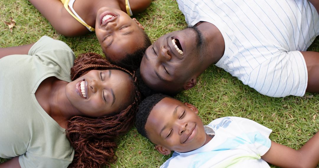 Joyful Family Relaxing on Grass Outdoors Smiling Together
