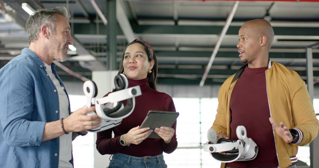 Diverse team testing VR headsets and wearables in industrial workshop for product demo