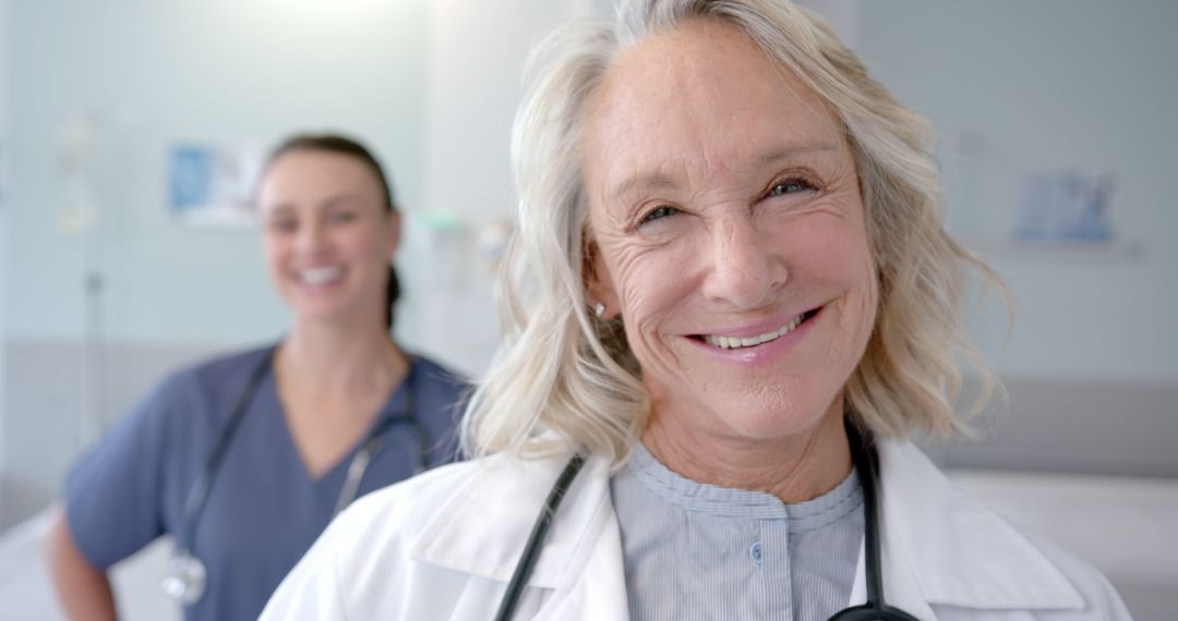 Experienced Female Doctor Smiling, Nurse in Background - Free Images, Stock Photos and Pictures on Pikwizard.com