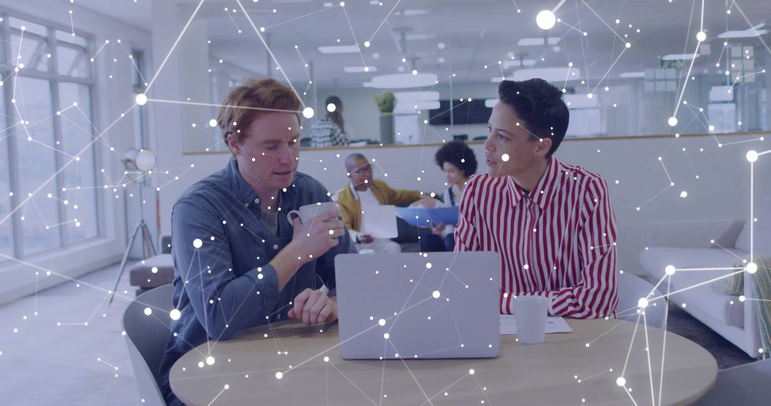 Colleagues collaborating over laptop and coffee in modern open office with network overlay