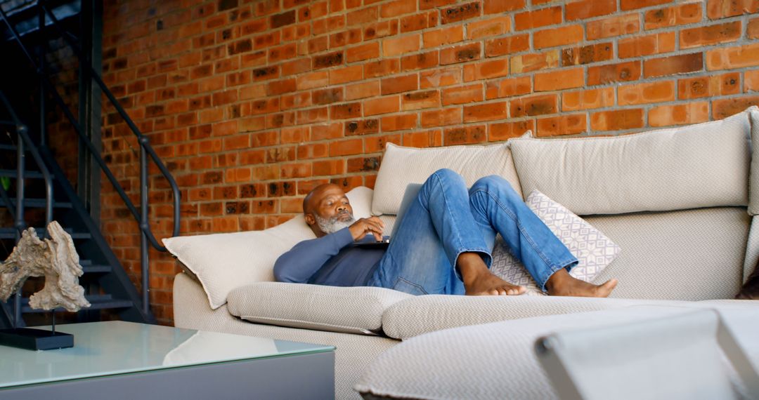 Man Relaxing on Couch Using Laptop in Cozy Living Room - Free Images, Stock Photos and Pictures on Pikwizard.com