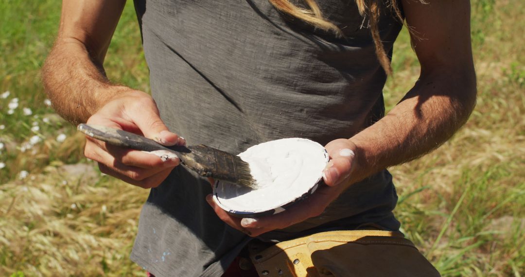 Close-Up of Man Holding Paintbrush and Mixing Paint Outdoors - Free Images, Stock Photos and Pictures on Pikwizard.com