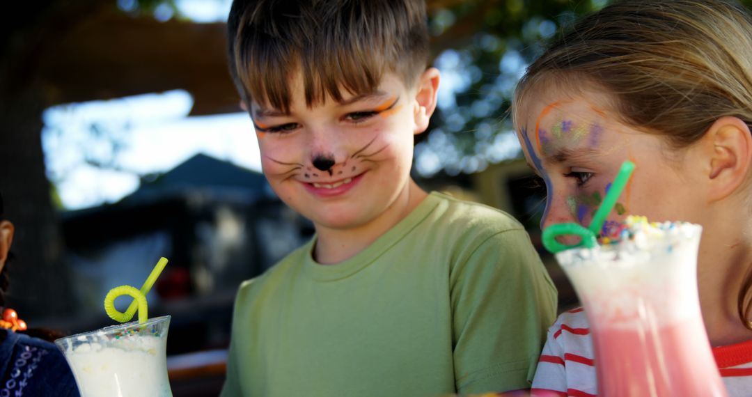 Children Enjoying Milkshakes at Outdoor Party with Face Paint - Free Images, Stock Photos and Pictures on Pikwizard.com