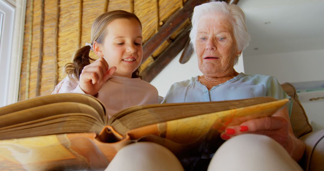 Happy Granddaughter Reading Book with Elderly Grandmother in Cozy Room - Free Images, Stock Photos and Pictures on Pikwizard.com