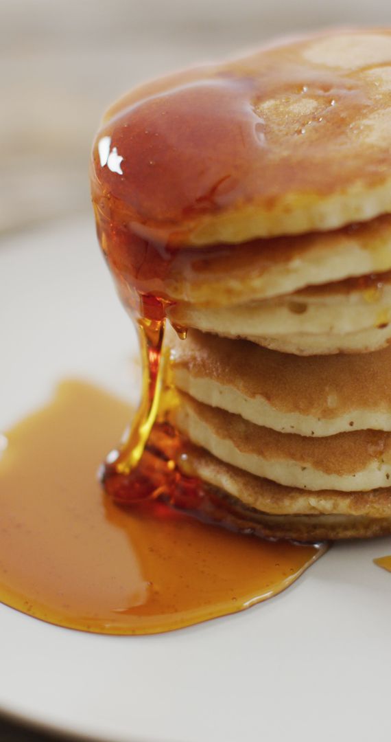 Maple Syrup Pouring onto Fluffy Pancake Stack