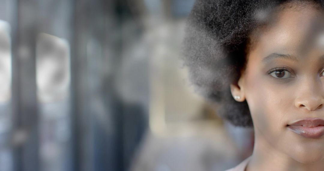 Young woman behind storefront glass with soft reflections and contemplative expression