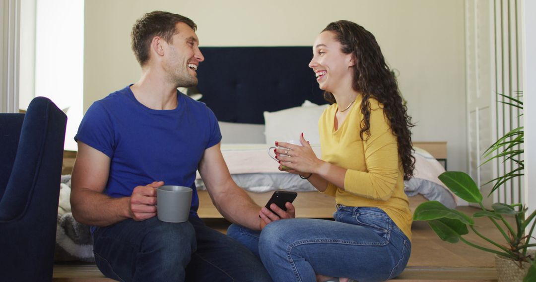 Happy Couple Enjoying Coffee Break with Smartphone at Home