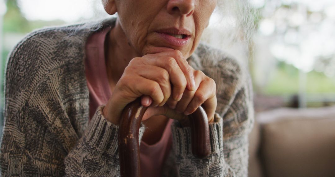 Elderly woman leaning on cane contemplating life indoors - Free Images, Stock Photos and Pictures on Pikwizard.com