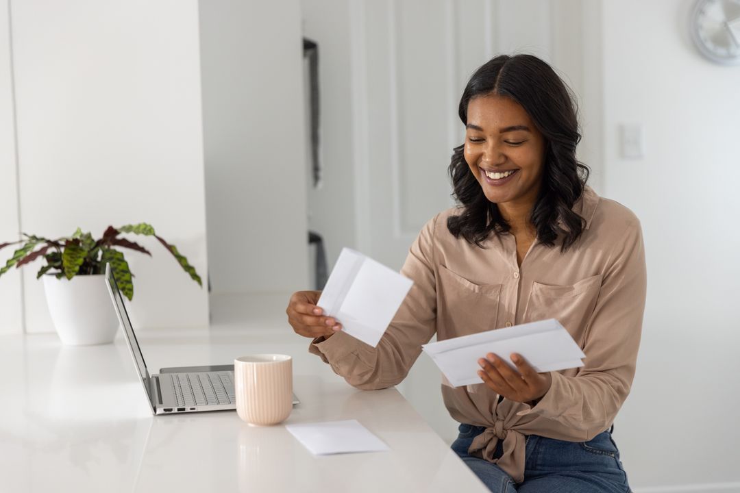 Smiling African American Woman Sorting Envelopes at Home Workspace