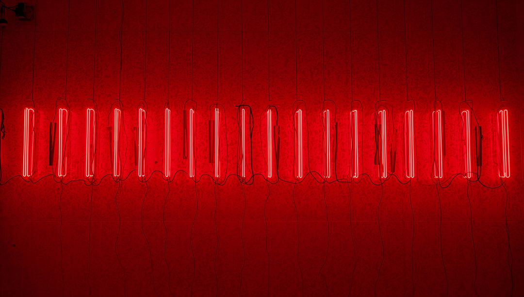 Glowing Vertical Red Neon Tube Installation Spanning Gallery Wall with Visible Cables