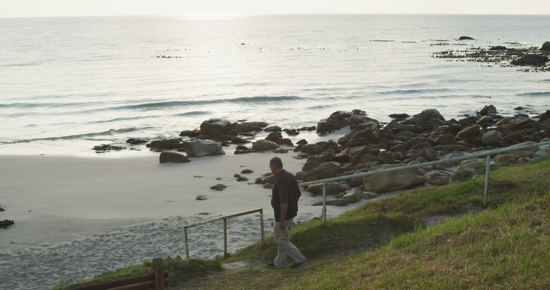 Man Walking Down to Seaside Rocks at Sunset - Free Images, Stock Photos and Pictures on Pikwizard.com