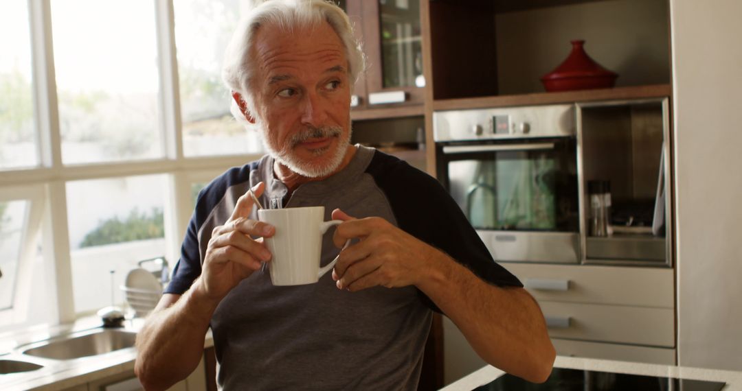 Older Man Relaxing with Morning Coffee in Modern Kitchen - Free Images, Stock Photos and Pictures on Pikwizard.com