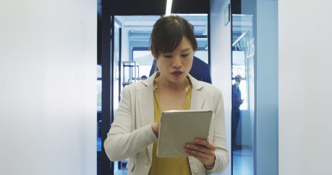 Focused Businesswoman Using Tablet in Office Corridor - Free Images, Stock Photos and Pictures on Pikwizard.com