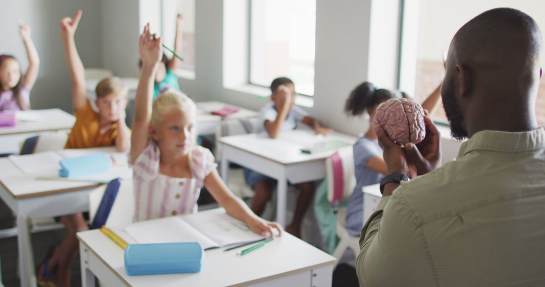 Image of african american male teacher and diverse pupils raising hands during lessons - Free Images, Stock Photos and Pictures on Pikwizard.com