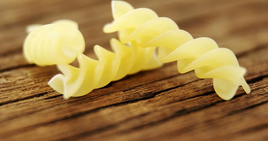 Close-up of Two Spiral Pasta Pieces on Rustic Wood Surface - Free Images, Stock Photos and Pictures on Pikwizard.com