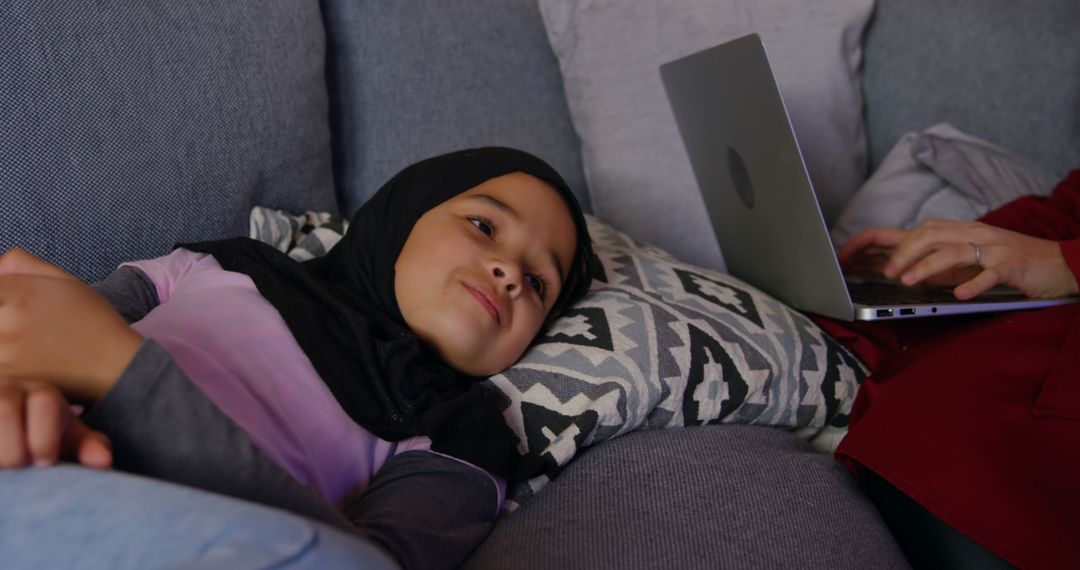 Young Girl Wearing Hijab Lounging on Couch Watching Laptop, Curious and Engaged - Free Images, Stock Photos and Pictures on Pikwizard.com