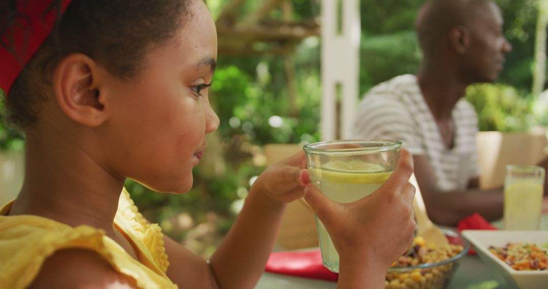 Young girl drinking lemonade at family picnic outdoors - Free Images, Stock Photos and Pictures on Pikwizard.com