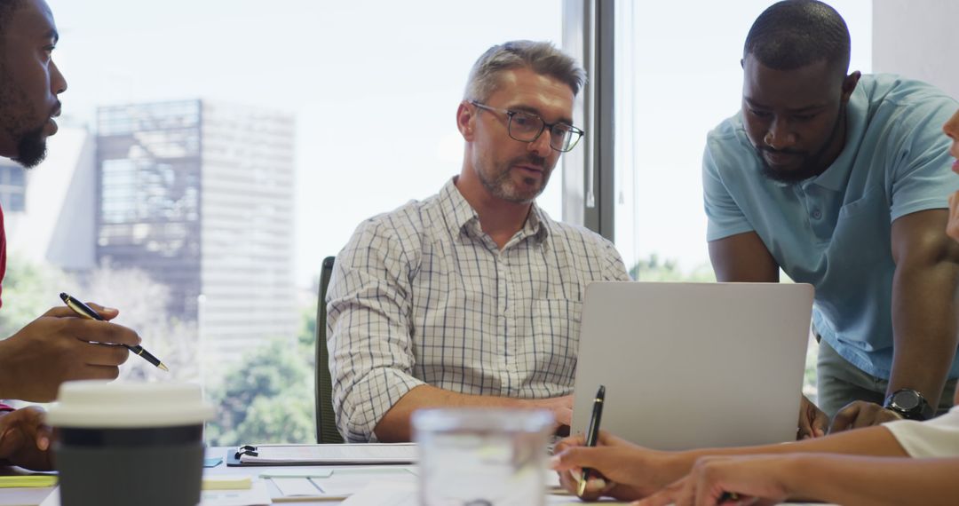 Diverse Professionals Collaborating in Modern Office on a Laptop