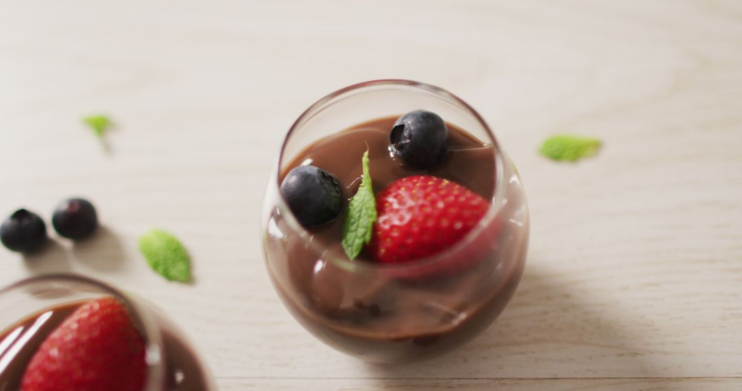 Image of chocolate pudding with strawberries and bluberries on a wooden surface - Free Images, Stock Photos and Pictures on Pikwizard.com