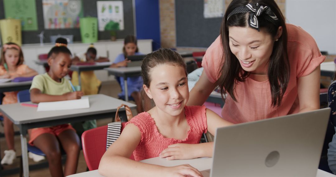 Female Teacher Assisting Students with Laptops in Classroom