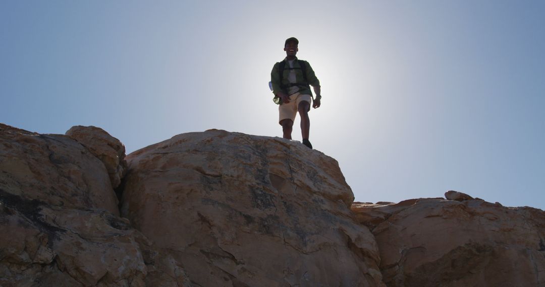 Hiker Standing on Rocky Cliff with Sun Backlight - Free Images, Stock Photos and Pictures on Pikwizard.com