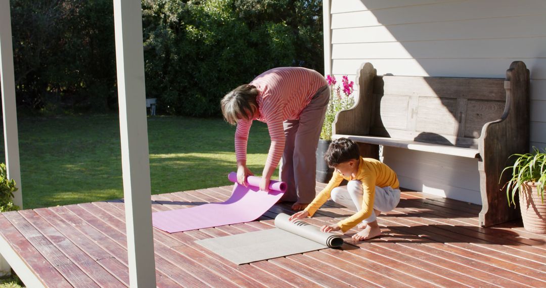 Child and Elderly Woman Rolling Out Yoga Mats on Porch - Free Images, Stock Photos and Pictures on Pikwizard.com