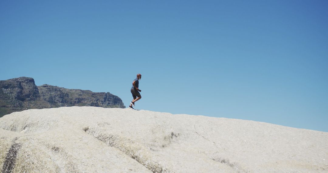 Man Hiking on Rocky Terrain with Clear Blue Sky - Free Images, Stock Photos and Pictures on Pikwizard.com