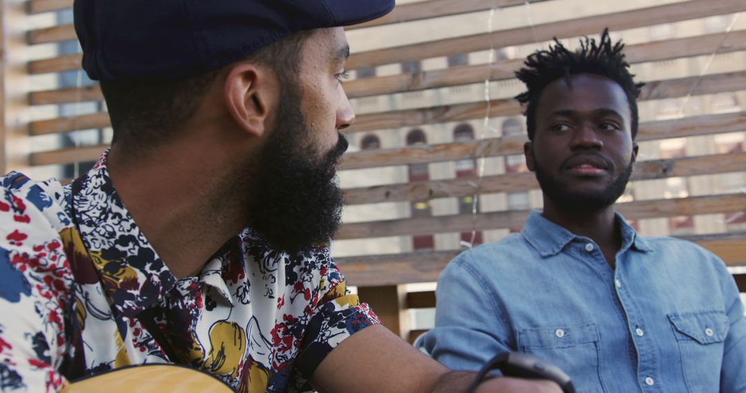 Two Young Men Having Conversation with Guitar on Rooftop Patio