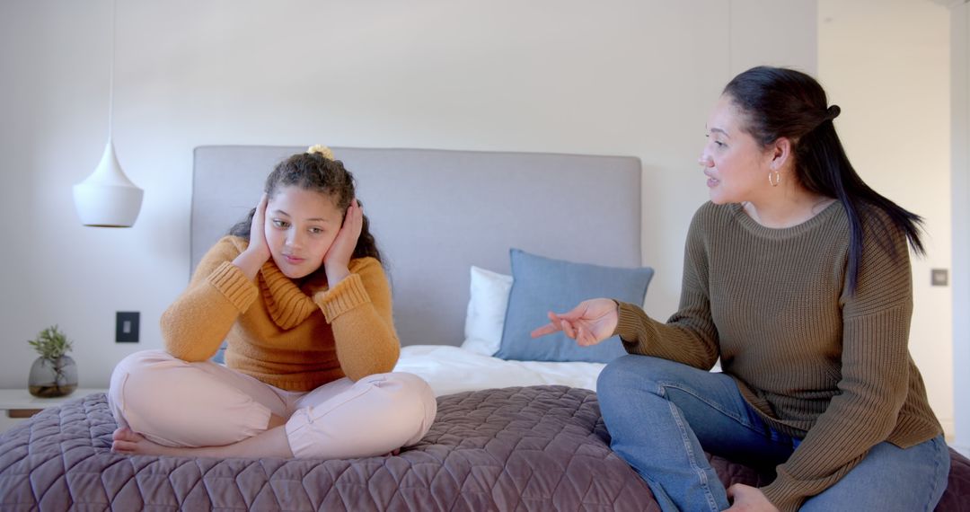 Mother discussing disagreement with troubled daughter on bed - Free Images, Stock Photos and Pictures on Pikwizard.com