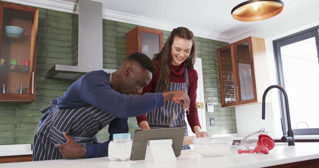 Diverse Couple Baking Together in Modern Kitchen Using Tablet