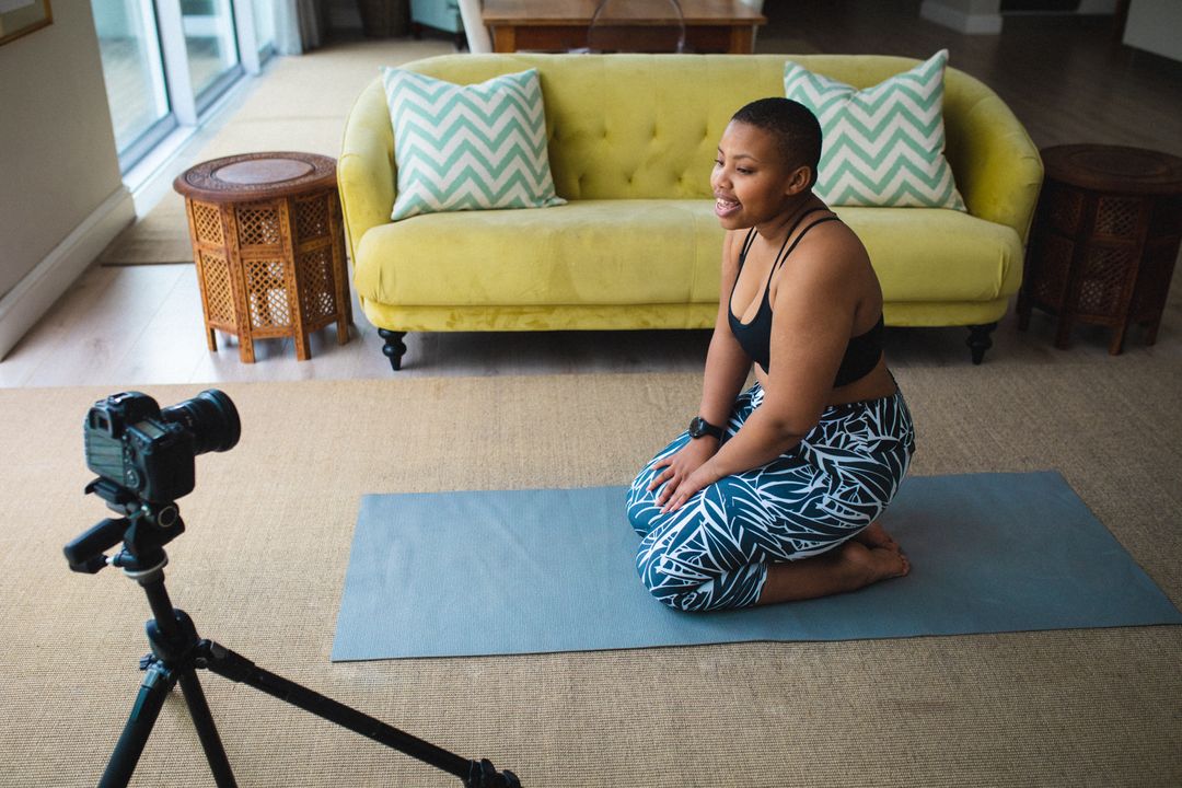 African american female blogger recording a video on digital camera sitting on yoga mat at home - Free Images, Stock Photos and Pictures on Pikwizard.com