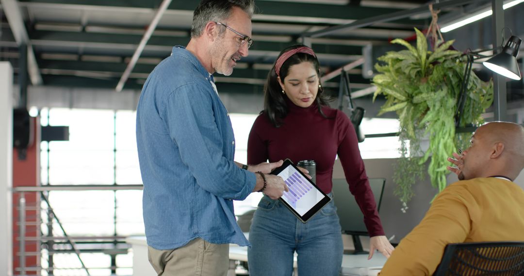 Diverse team discussing tablet charts and strategy in modern open-plan office
