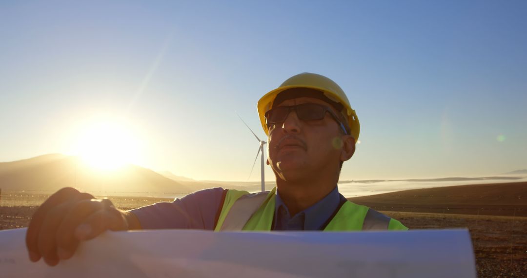 Engineer inspecting wind turbine with blueprint at sunrise - Free Images, Stock Photos and Pictures on Pikwizard.com