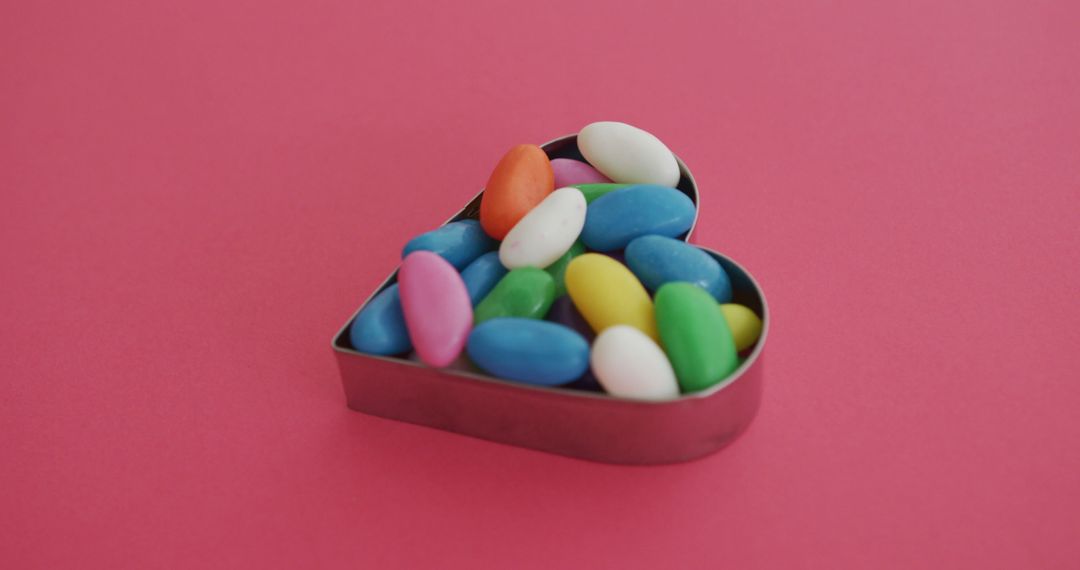 Colorful candy beans in heart-shaped container on pink background - Free Images, Stock Photos and Pictures on Pikwizard.com