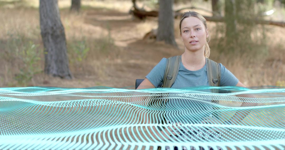 Woman hiker wearing teal tee carrying backpack on pine trail with turquoise grid overlay
