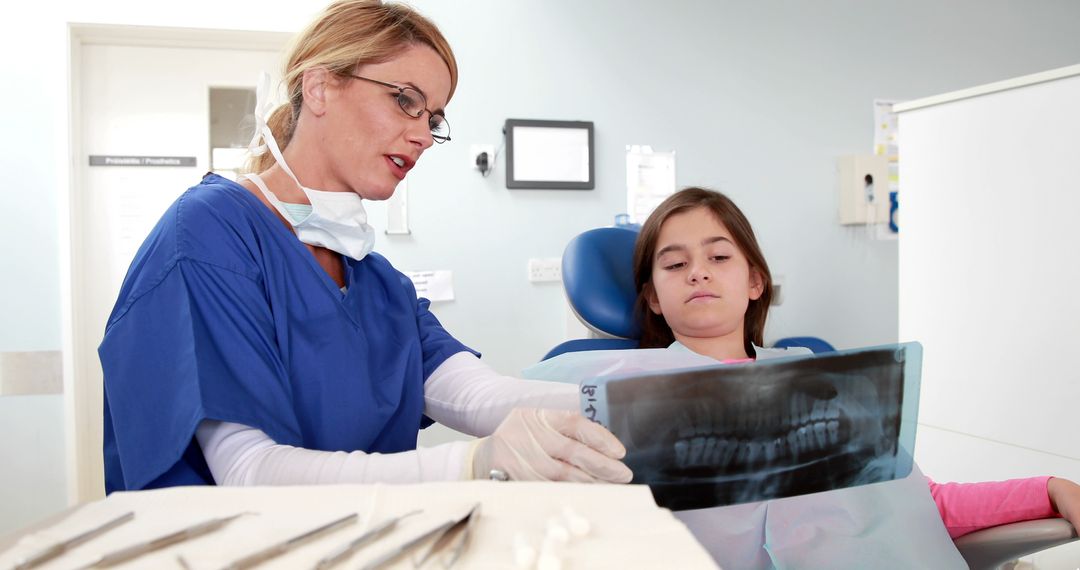 A Caucasian female dentist is showing a young girl her dental X-ray, with copy space - Free Images, Stock Photos and Pictures on Pikwizard.com