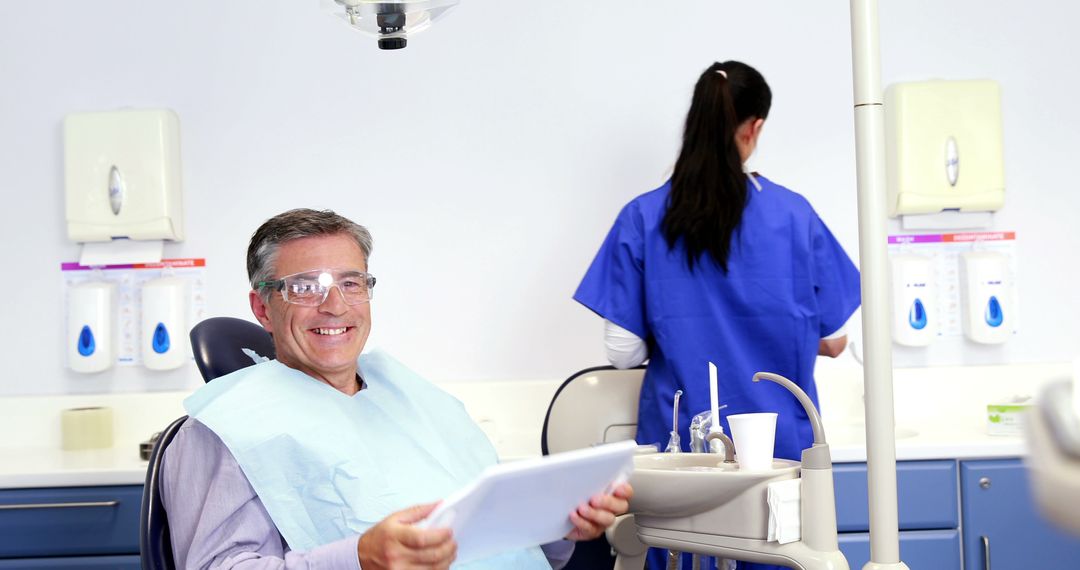 Mid-Aged Man Relaxed in Dental Clinic Holding Dental Records - Free Images, Stock Photos and Pictures on Pikwizard.com