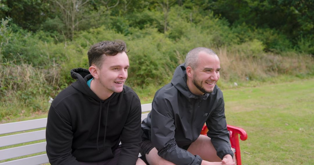 Two Men Relaxing on Bench in Park Enjoying Conversation
