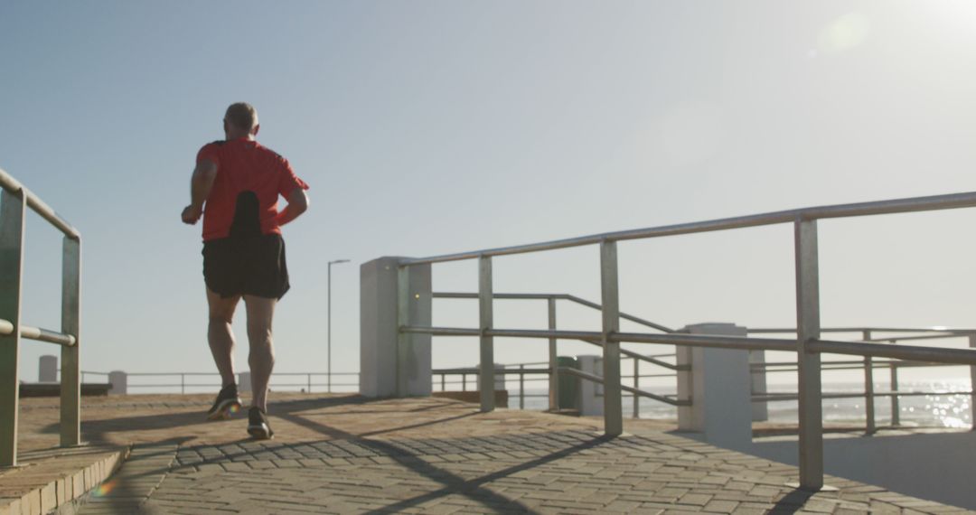 Man Running on Seaside Promenade on Sunny Day - Free Images, Stock Photos and Pictures on Pikwizard.com