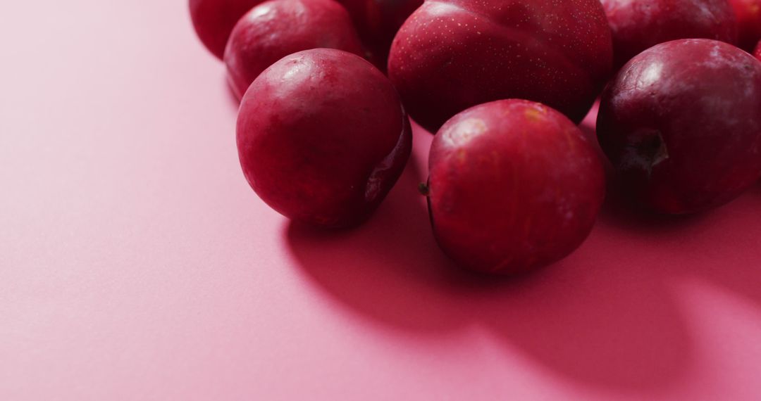 Image of fresh plums lying on pink surface - Free Images, Stock Photos and Pictures on Pikwizard.com