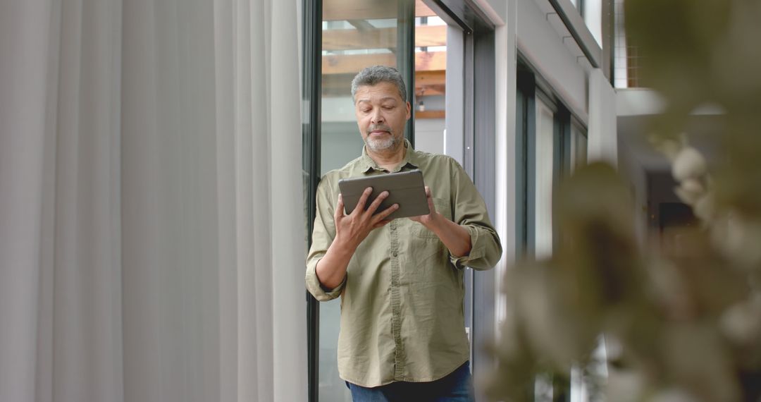 Middle-aged Man Using Tablet in Modern Home Interior - Free Images, Stock Photos and Pictures on Pikwizard.com