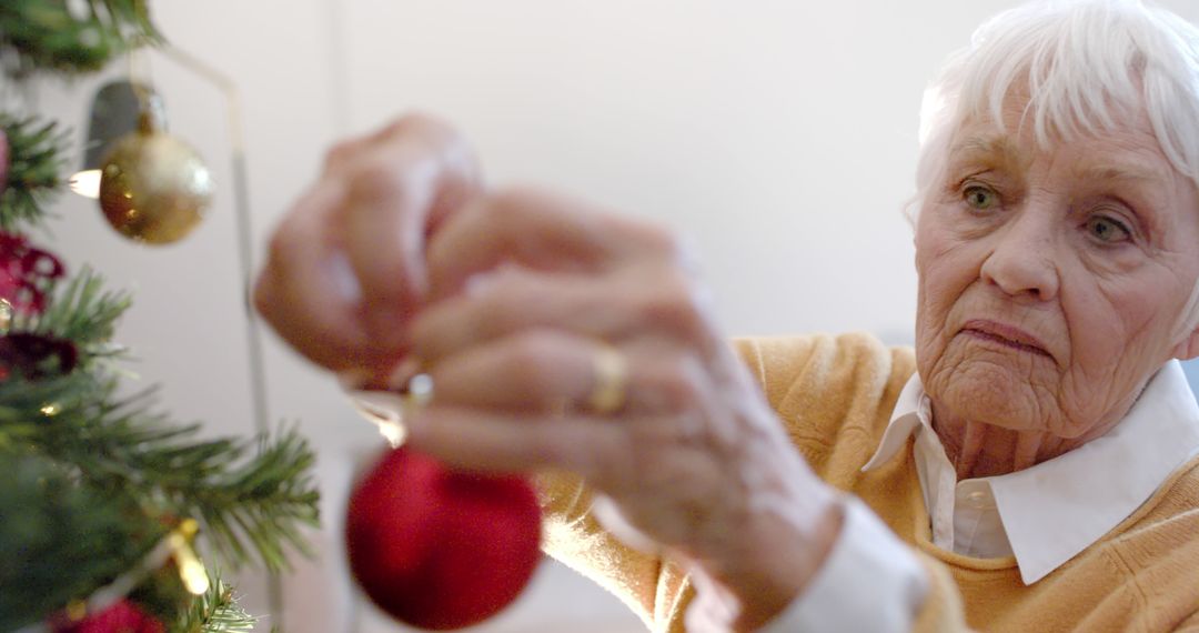 Senior Woman Decorating Christmas Tree at Home in Daylight - Free Images, Stock Photos and Pictures on Pikwizard.com