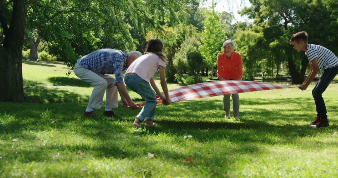 Grandparents and Grandchildren Spreading Picnic Blanket in Park - Free Images, Stock Photos and Pictures on Pikwizard.com