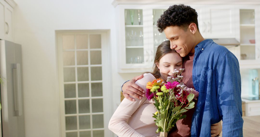 Young Couple Embracing in Modern Kitchen with Bouquet of Flowers - Free Images, Stock Photos and Pictures on Pikwizard.com