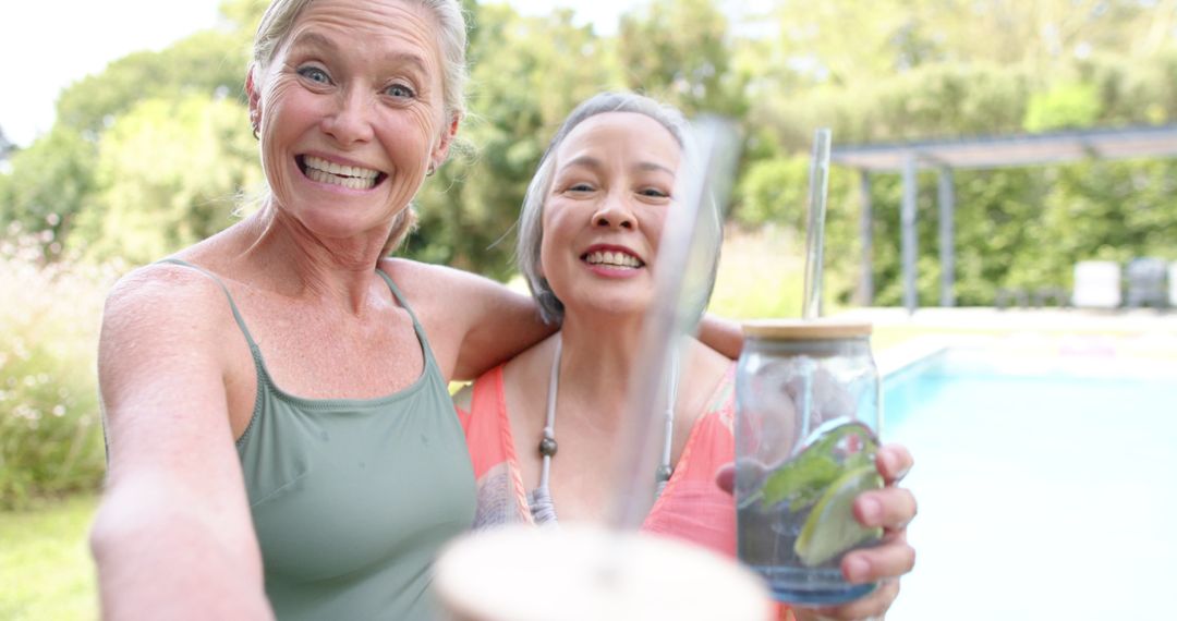 Joyful Senior Women Celebrating by the Poolside with Refreshing Drinks