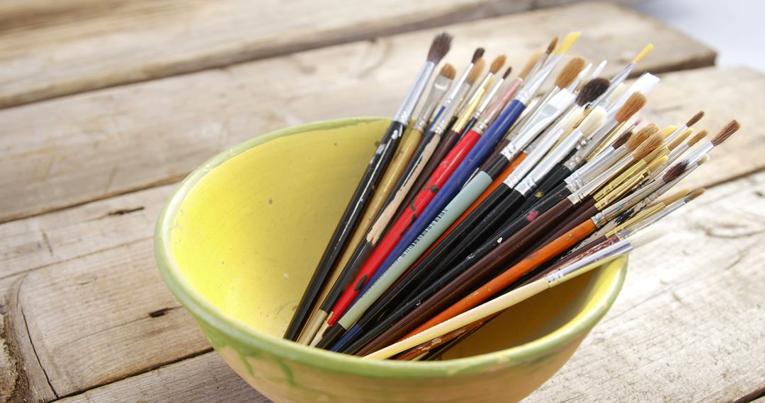 Assorted Paint Brushes in Yellow Bowl on Wooden Table - Free Images, Stock Photos and Pictures on Pikwizard.com