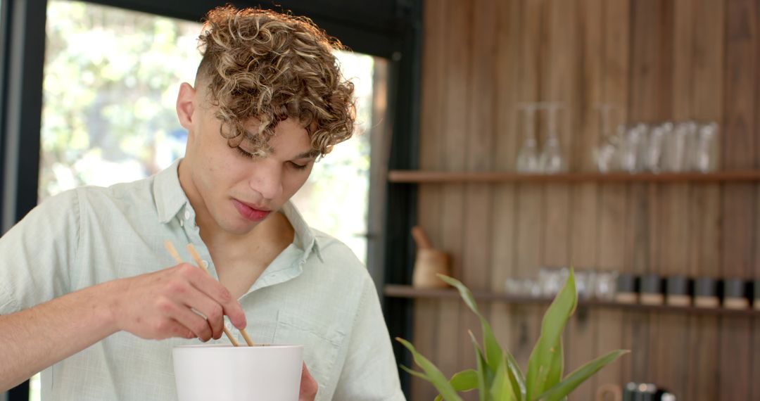 Man Stirring Noodles with Chopsticks in Contemporary Kitchen